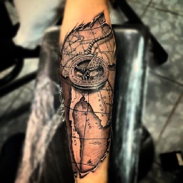 Uskomaton veistävä tatuointi maailmankartalla ja merikompassilla kyynärvarressa