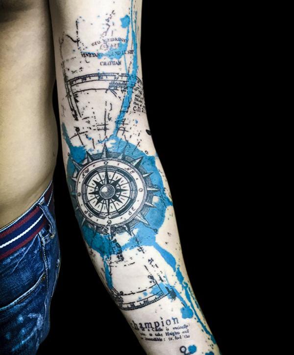 Täyshihainen tatuointi, jossa on merikompassi ja kartta vesiväreillä
