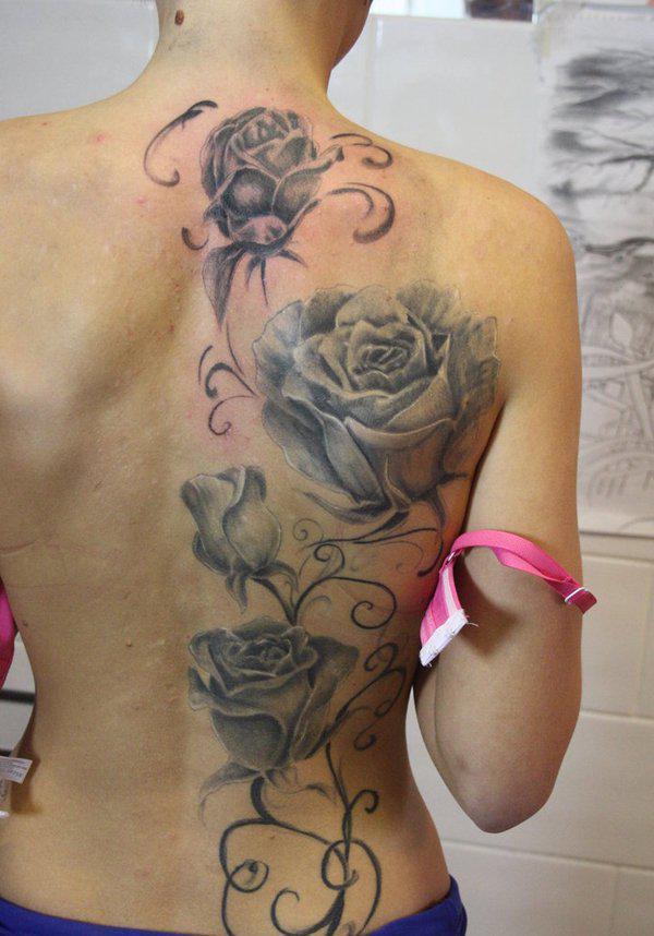 Neljä ruusua tatuoitu harmaasävyisenä puoleen selästä