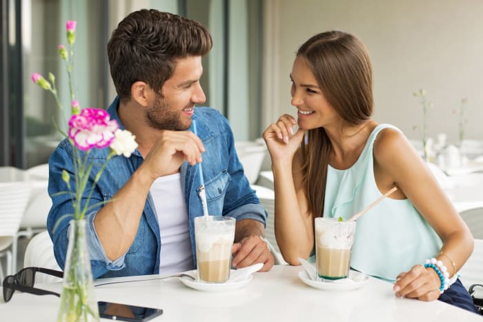 Hymyilevä pari kahvilassa nauttien toistensa kanssa vietetystä ajasta
