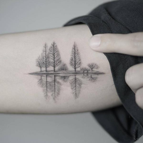 Pienet puut heijastus vedessä pieni käsivarsi tatuointi