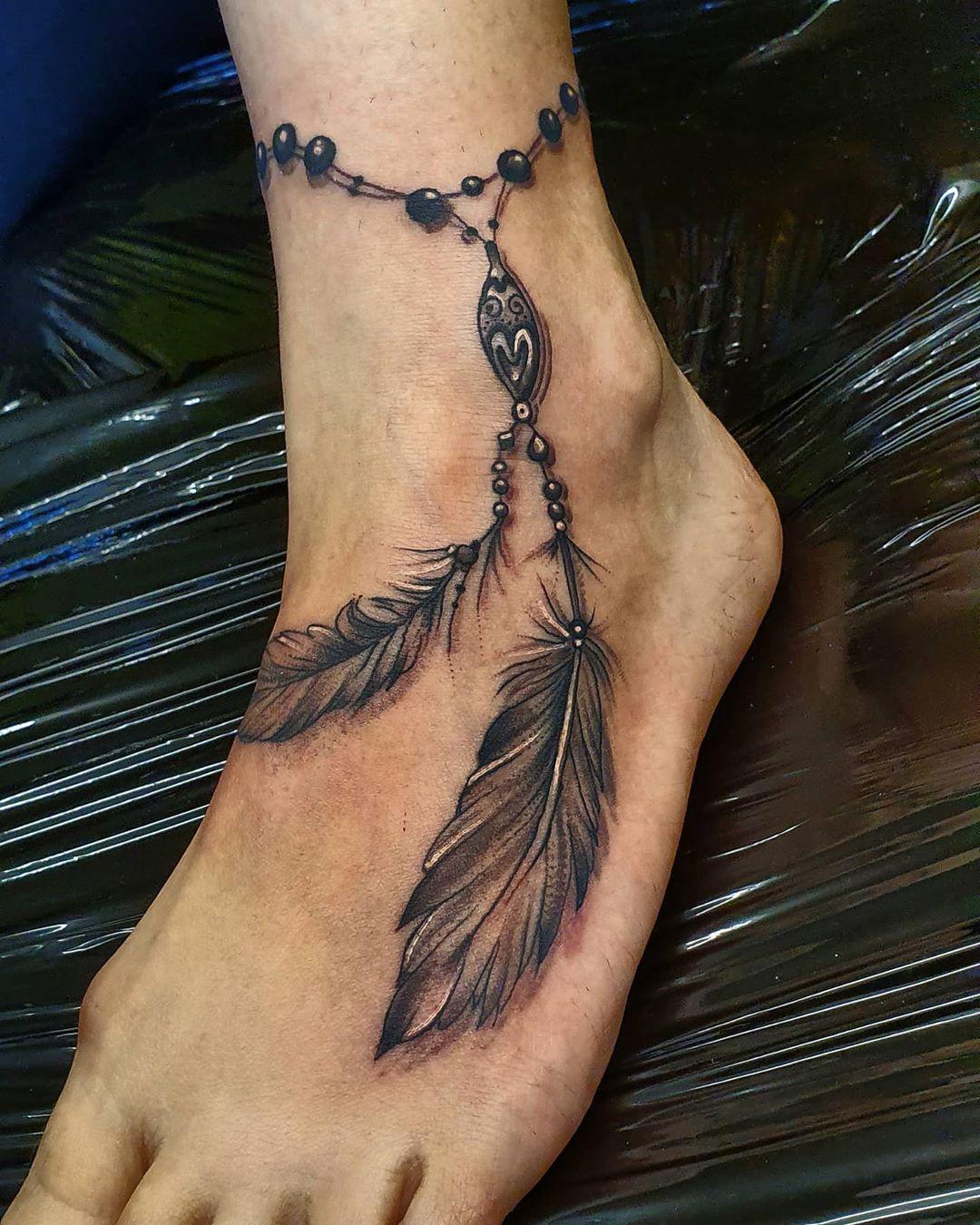 Mustavalkoinen tatuointi nilkkarannekkeella höyhen kanssa alkuperäiskansojen tyyliin