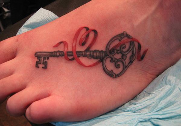 Realistinen tatuointi mustalla avaimella ja punaisella nauhalla
