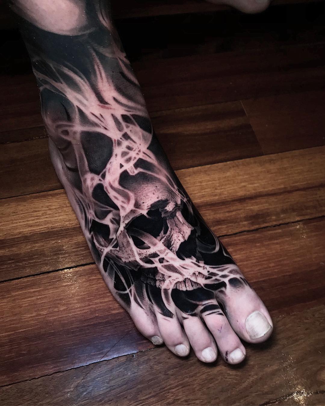 Μαύρο και άσπρο τατουάζ ποδιών με κρανίο στη φωτιά