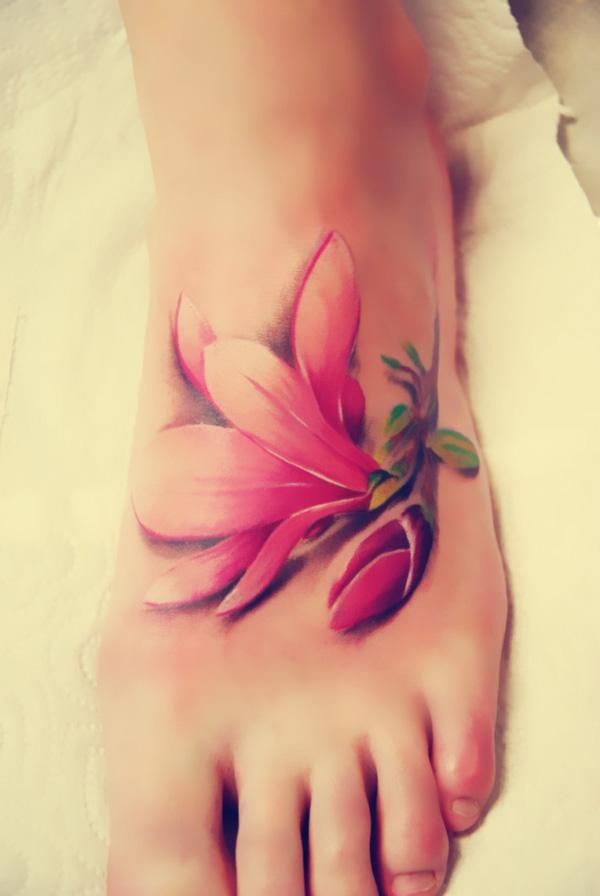 Den realistiske magnolia -tatovering ligner et stykke blomst, der falder på foden