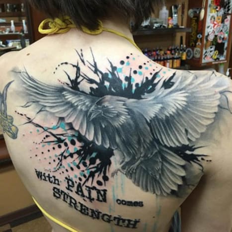 Ravn og citat tilbage tatovering Denne kvindes tatovering på ryggen blev inked af Josh A. fra Clever Rebel Tattoo i staten Washington og har et sort -hvidt billede af en ravn på flugt med citatet 