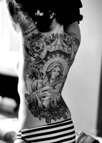Neitsyt Marian ja ruusujen tatuointi Tämä suuri selkätatuointi sisältää useita erilaisia ​​mustavalkoisia kuvia, mukaan lukien Neitsyt Marian muotokuva, jolla on Jeesus -vauva edessä ja keskellä. Neitsyt Marian alla on joukko kukkivia ruusuja, ja yläpuolella on maailmanpyörä, sirkusteltta ja kaksi luusta, jossa on viikset.