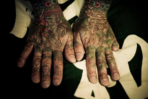 Tatoverede hænder med et ciffer mangler. En traditionel japansk tatovering, som den ofte bruges af Yakuza, er en meget gammel og tidskrævende proces til manuelt at stikke en pind med på punktet flere skarpe nåle i huden. Dette skal ske i en præcis vinkel (afhængigt af hudtykkelse) og med en præcis hastighed (120/minut), og dette er en færdighed, som kun traditionelle japanske tatoveringsmestre besidder. Resultatet er en forvikling, en farvepalet og et mønster, som ikke er muligt med den moderne måde at tatovere med en maskine på. Tatovøreren Hori Sensei inviterer dig, han tager ikke imod faste kunder. Med ham tager det cirka 100 timer at gennemføre en traditionel japansk tatovering, kan koste op til $ 10.000, og der skal laves en tidsplan for daglige eller ugentlige besøg. Som klient har du kun lidt at sige til tatoveringens design. Hori Sensei bestemmer, hvad der er bedst for dig efter at have taget tid til at tale med dig og lære dig at kende. Kun få traditionelle japanske tatoveringseksperter lever stadig i dag i Japan. - 2009