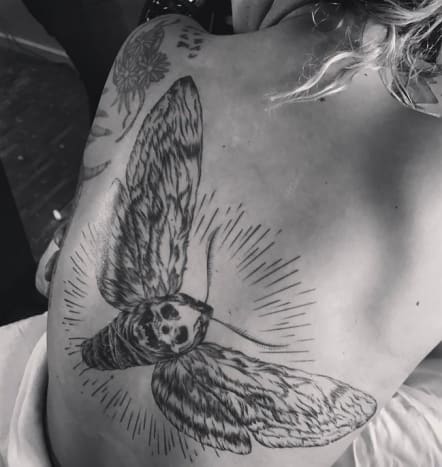 (Φωτογραφία: Lady Gaga/Instagram) Το τατουάζ της Lady Gaga καταλαμβάνει το μεγαλύτερο μέρος της πλάτης της, που εκτείνεται από την αριστερή ωμοπλάτη στη δεξιά πλευρά και διαθέτει μια μαύρη και γκρι εικόνα ενός γερακιού με το κεφάλι του θανάτου. Προκειμένου να προετοιμαστεί για την εμφάνιση της στα Grammy με τους Metallica, η τραγουδίστρια σημείωσε στο Instagram ότι «άκουγε Metallica όλη μέρα και γλέντι με τους φίλους μου και μετά έπαιζε μαζί τους στα Grammy», και ήταν στις 12 Φεβρουαρίου, λίγο πριν ανέβηκε στη σκηνή με τους Metallica, όπου η Gaga έδειξε το γιγαντιαίο τατουάζ της με σκώρο στο Instagram, λέγοντας τη ασπρόμαυρη φωτογραφία, 