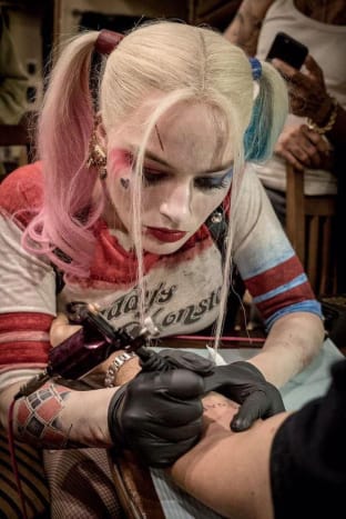 Hänen hääpäivänsä ei tietenkään ole ensimmäinen kerta, kun Margot Robbie tatuoi ystävänsä. Hän antoi useille tähtitovereilleen SKWAD-tatuointeja muistoksi yhteisestä ajastaan ​​kuvatakseen vuoden 2016 kesäleffan Suicide Squad, ja myös kirjoitti joukon emoji-hymiötatuointeja Cara Delevingnen varpaille suunnilleen samaan aikaan. Robbie on ensimmäinen, joka myöntää, ettei hän ole paras tatuoinnissa-hän vertaa muotoiluaan ”siihen, mitä 4-vuotias piirtää ja kiinnittää jääkaappisi”-mutta se ei estänyt häntä värjäämästä häävieraita!