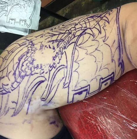 Ο Τζάκσον κατέγραψε ολόκληρη τη συνεδρία τατουάζ στον λογαριασμό του στο Instagram, μοιράζοντας φωτογραφίες από το στένσιλ πριν το τατουάζ, βίντεο από τον καλλιτέχνη τατουάζ, Τζάστιν Λιούις, που εργάζεται στο μελάνι και μερικά στιγμιότυπα του τελικού προϊόντος. Ο Λιούις μοιράστηκε επίσης μια φωτογραφία του τατουάζ του Τζάκσον σε στιλ πανοπλίας στο Instagram, γράφοντας: «μέχρι την επόμενη συνεδρίαση ο αδελφός μου το σκότωσε σήμερα 4 ώρες.» Ωστόσο, καμία αναφορά στα λάθη του τατουάζ.
