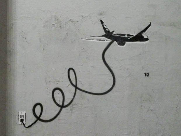 Fly By Wire - Los Angeles Street -taiteilija - PLASTIC JESUS ​​pyyhkäisee Boeingin ongelmiin sen lippulaivassa 787 Dreamliner. Stenciled graffiti havaittiin Los Angelesissa & apos; Melrose distict kuvaa lentokoneen, joka on kytketty pistorasiaan kaapelilla lentokoneen maadoitettujen sähköongelmien ratkaisemiseksi.