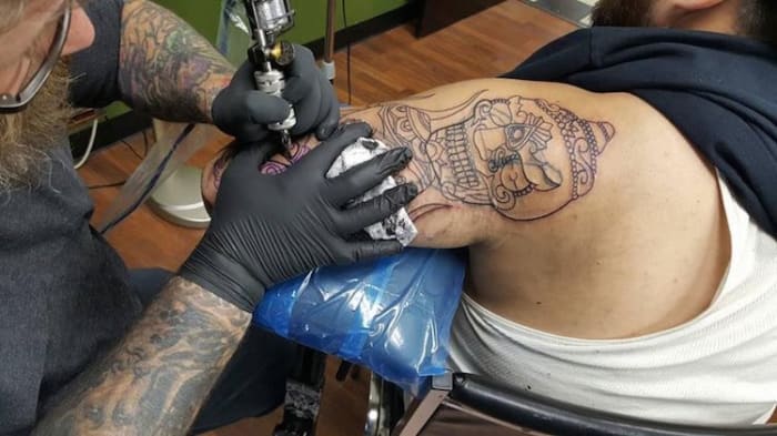 (Καλλιτέχνης Southside Tattoo που εργάζεται σε κάλυψη. Φωτογραφία: Southside Tattoo/Facebook) Εμπνευσμένη από την υποστήριξη που έλαβαν με αυτήν την πρωτοβουλία, η Elizabeth και ο σύζυγός της David Cutlip έχουν ξεκινήσει ακόμη και μια σελίδα GoFundMe με την ελπίδα να μαζέψουν 60.000 $ για να πάρουν αυτό το έργο σε μεγαλύτερη κλίμακα και εμπλέξτε περισσότερους καλλιτέχνες να παρέχουν καλύψεις ρατσιστικών και τατουάζ που σχετίζονται με συμμορίες. Τα χρήματα θα πάνε για έξοδα ταξιδιού και προμήθειας, σύμφωνα με τη σελίδα GoFundMe, από τα οποία, από σήμερα (8 Φεβρουαρίου), έχουν συγκεντρώσει $ 1.410. «Ο στόχος μας ήταν να βοηθήσουμε τα πρώην μέλη της συμμορίας στη Βαλτιμόρη να καλύψουν τα τατουάζ των συμμοριών και των ρατσιστών τους, ώστε να απαλλαγούν από τη συνεχή υπενθύμιση μιας προηγούμενης ζωής», αναφέρεται στη σελίδα GoFundMe του Southside Tattoo. «Έχουμε λάβει εκατοντάδες ερωτήσεις σχετικά με τη δουλειά, άλλες κοντά, άλλες μακριά. Είμαστε πραγματικά ταπεινωμένοι που έχουμε την ικανότητα να θεραπεύουμε τους άλλους μέσω της τέχνης μας ... χωρίς χορδές ».