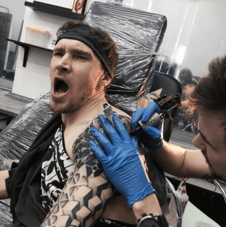 mand med smerter ved at blive tatoveret