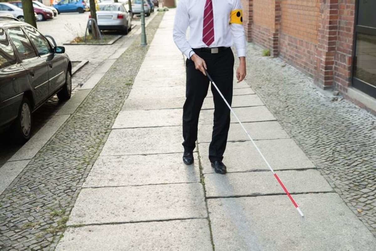 Kuvan kuvaus: Mies solmio- ja mekkohousuissa, jotka kävelevät ruokoilla pitkin naapuruston jalkakäytävää