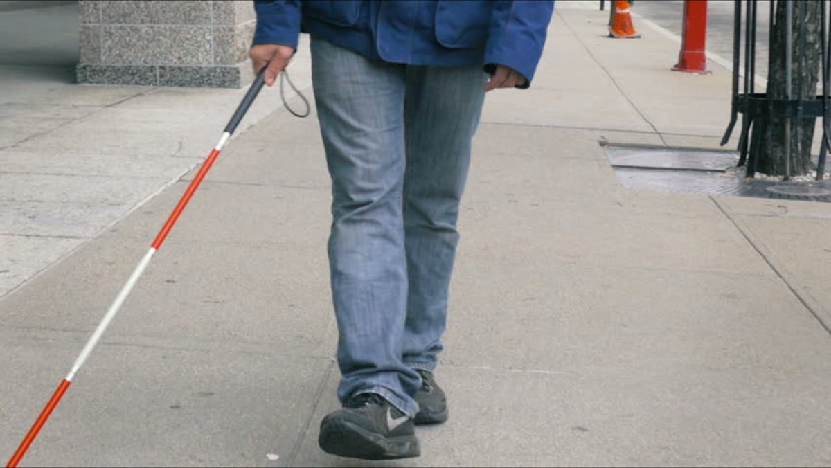 Valokuvan kuvaus: Mies farkkuissa ja lenkkarissa kävelemässä sokeriruo'on kanssa jalkakäytävällä